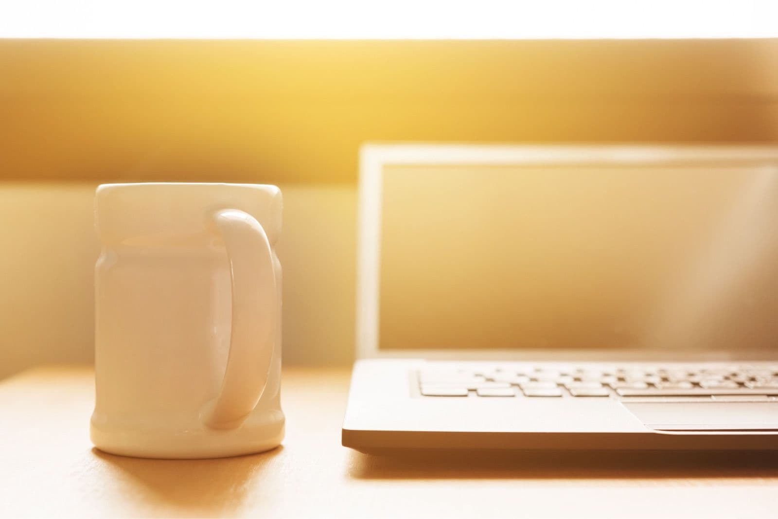 A laptop and a coffee mug adjacent to one another on a table
